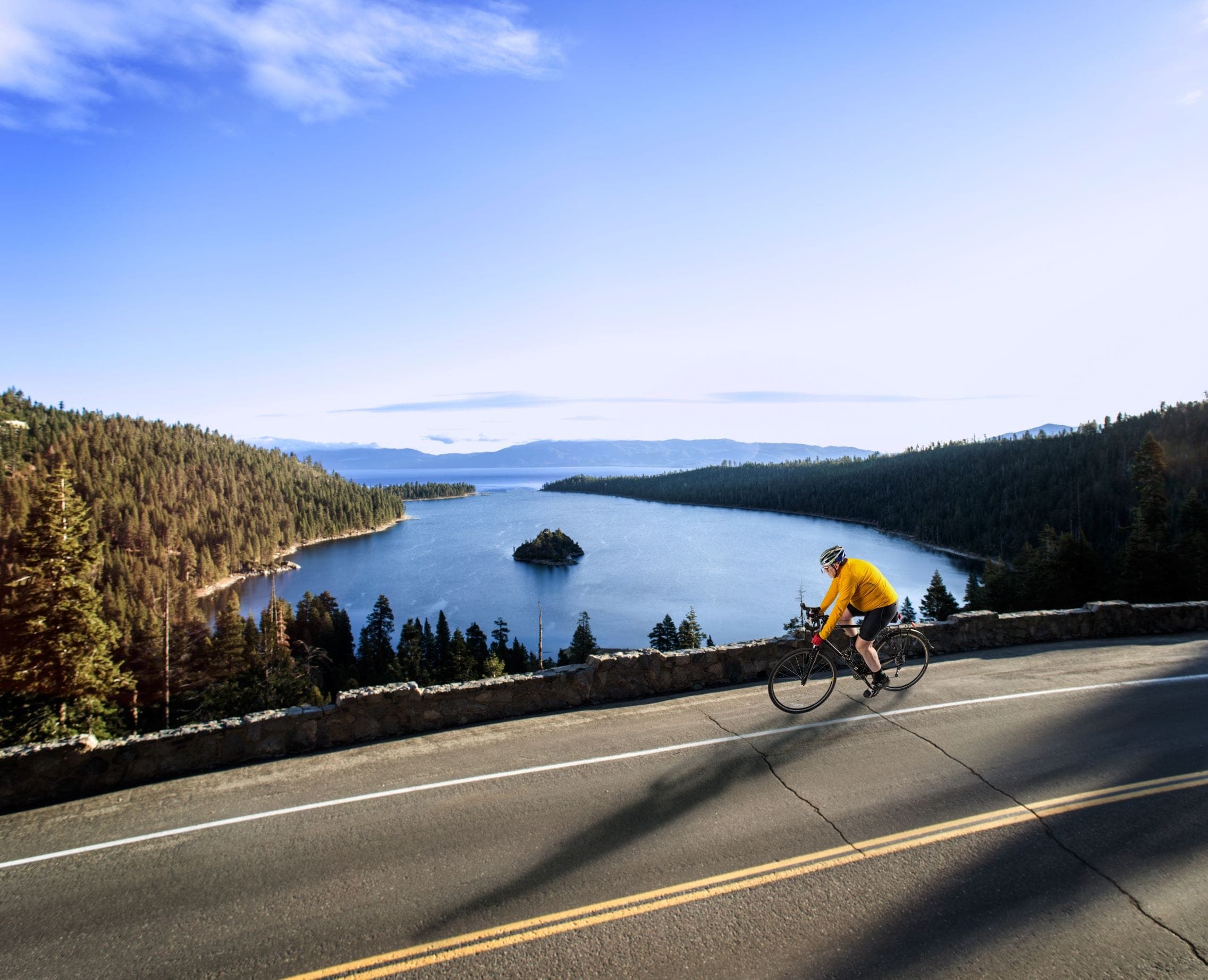 A road cyclist in a yellow jersey riding the highway above Emerald Bay