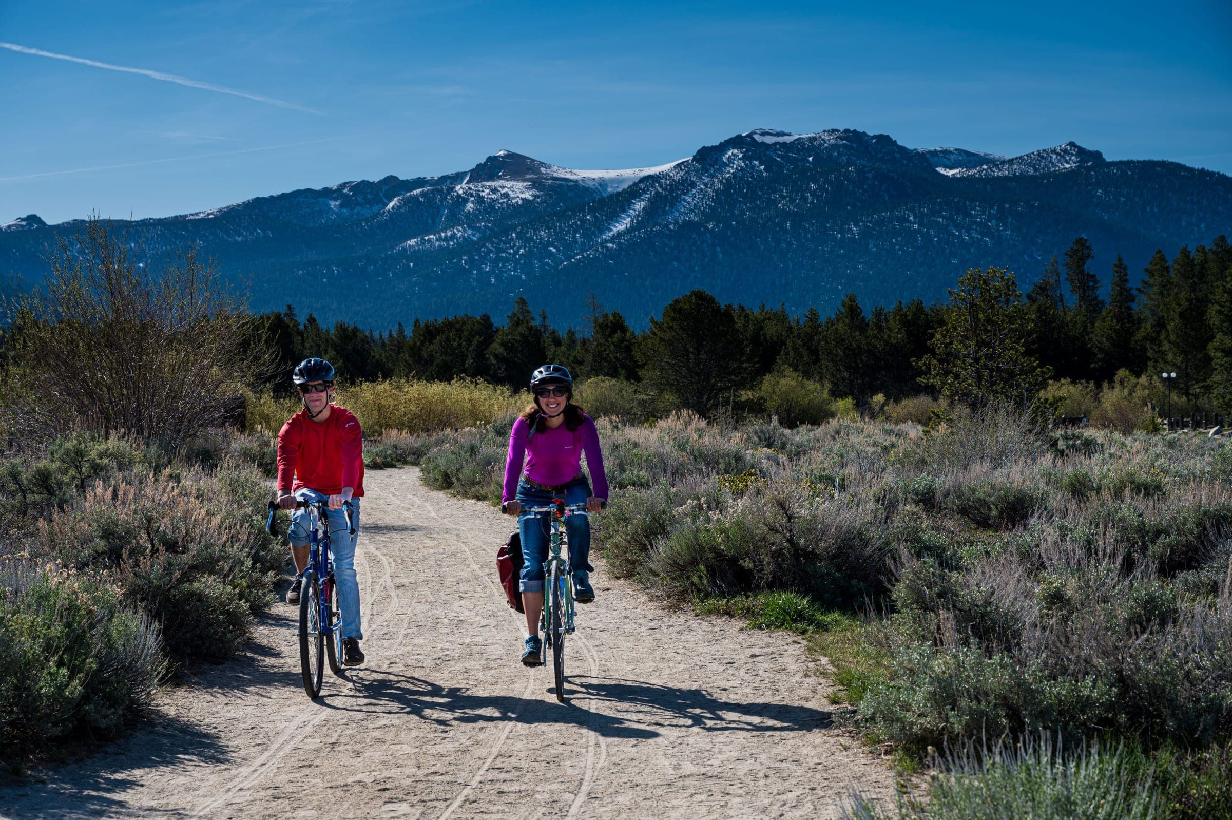 Two people biking the path through the Upper Truckee Marsh with mountains behind