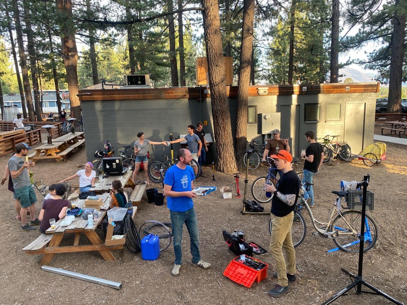 Volunteers repairing bikes on work stands at an outdoor Bike Kitchen fix-up event